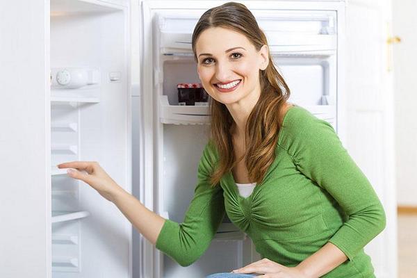  A girl stands near the open refrigerator